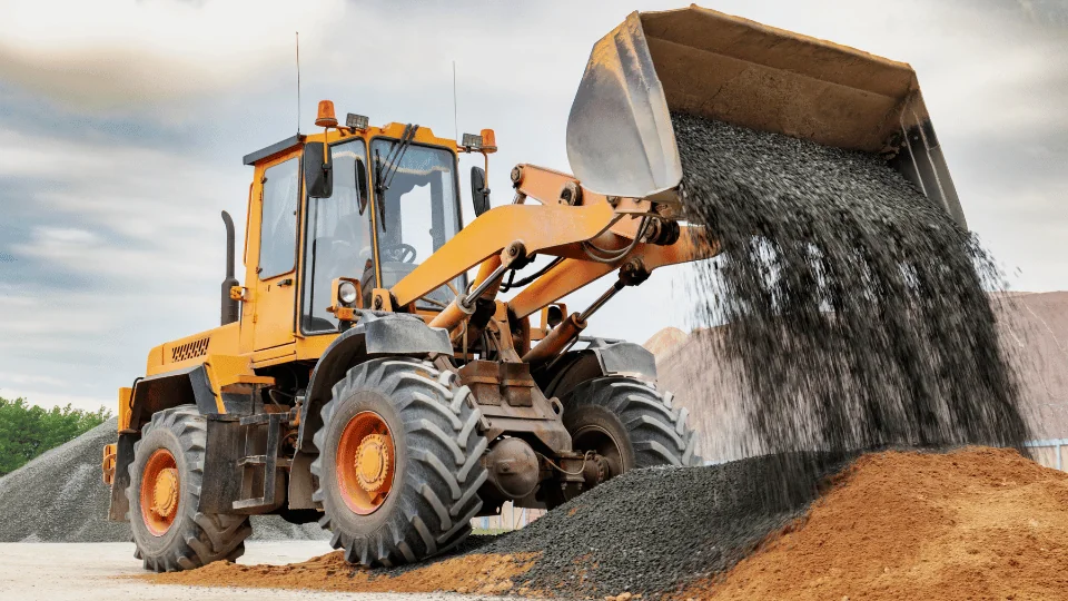 bulldozer dumping gravelly stone on top of waste pile