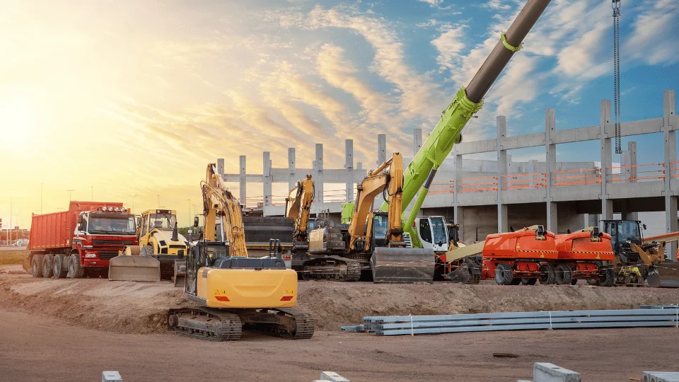 collection of heavy construction equipment at a construction site at sunset