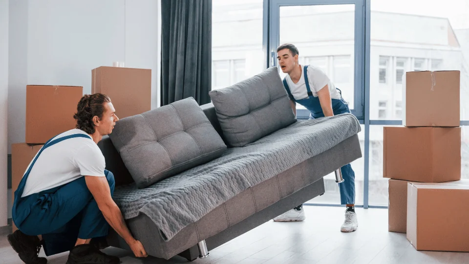 Shipping Furniture and Home Goods two workers lifting sofa in apartment