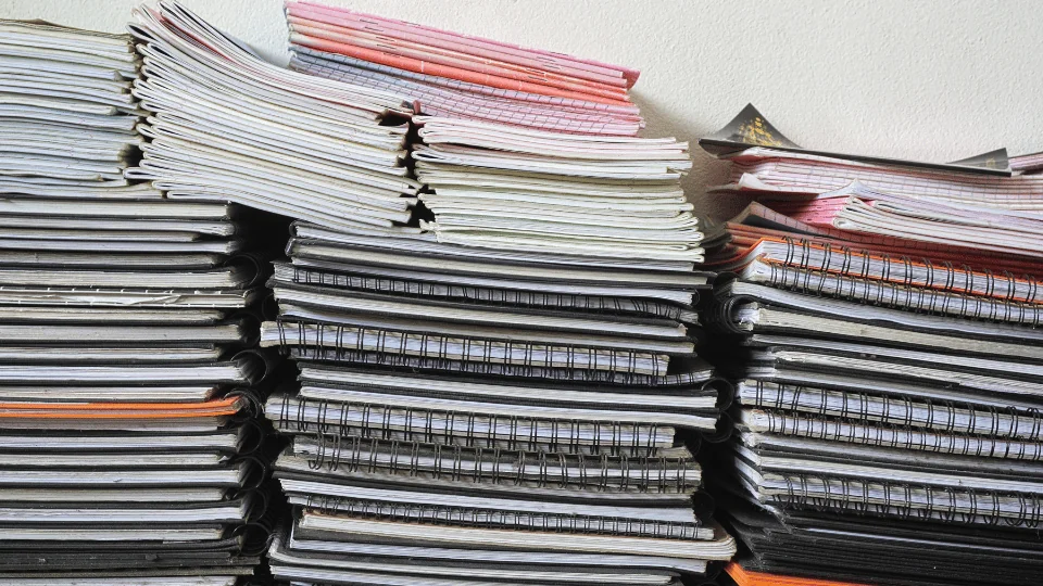 Shipping Paper and Paper Products stacks of notebooks against a white wall