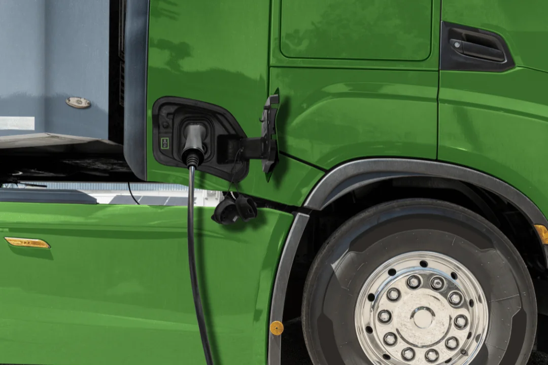 Green EV semi-truck being charged at a charging station